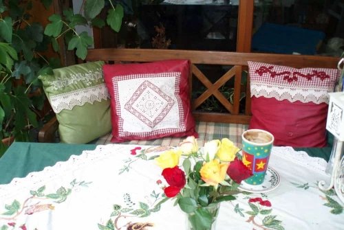 Sitzbank auf Terrasse mit Kissen und Tischdecke aus Outdoor-Dekostoffen